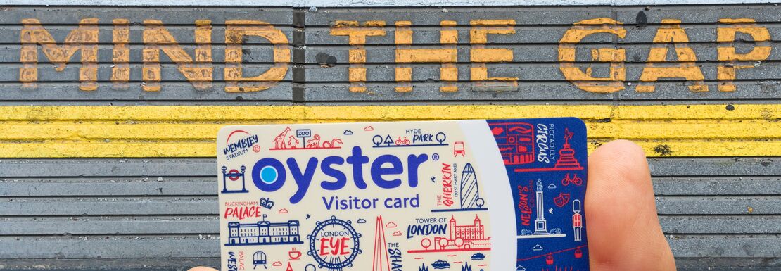A hand holding the Visitor Oyster card on a station platform