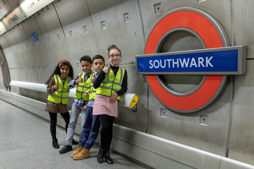 School students in hi-vis vests giving a thumbs up at Southwark tube station