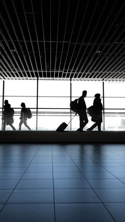 silhouette of people walking along an airport corridor
