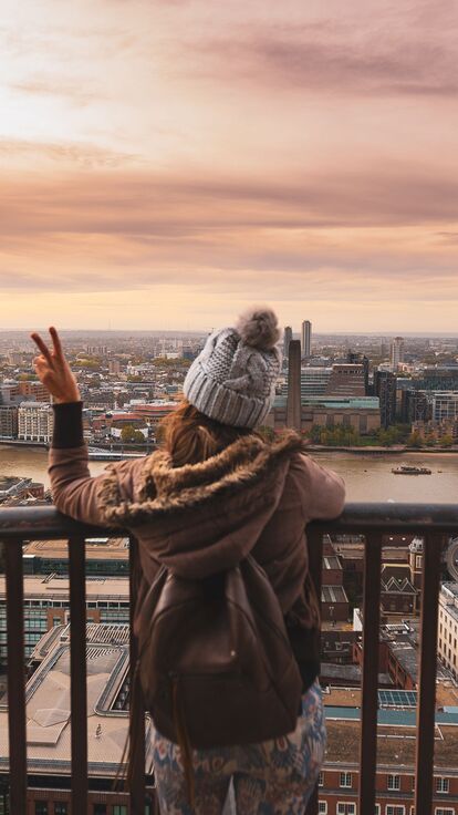 Woman at the top of St Paul's dome at sunrise with city view