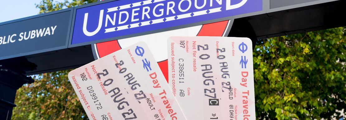 London day travelcards held up outside of an underground station in London